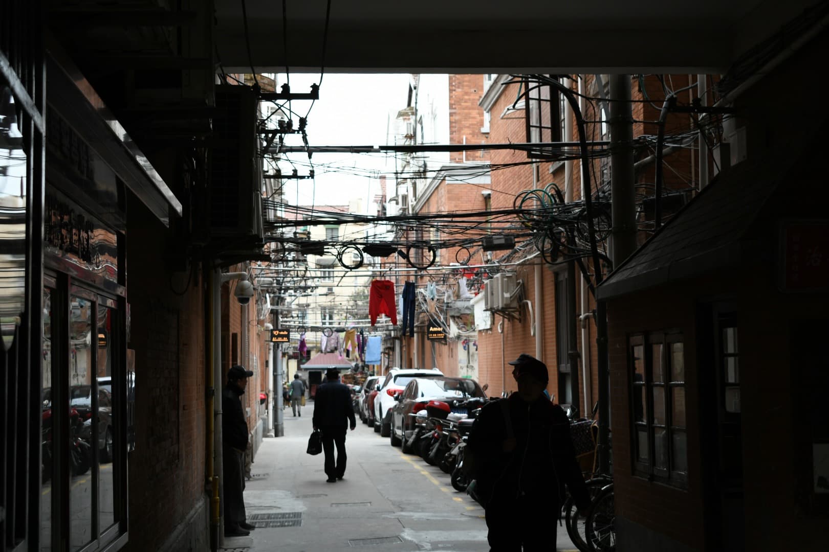 Shanghai Alley Shadows - A dimly lit alleyway in Shanghai, China, with clot...